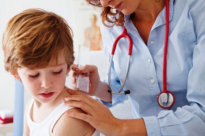 the doctor examines the child with a papilloma on the body